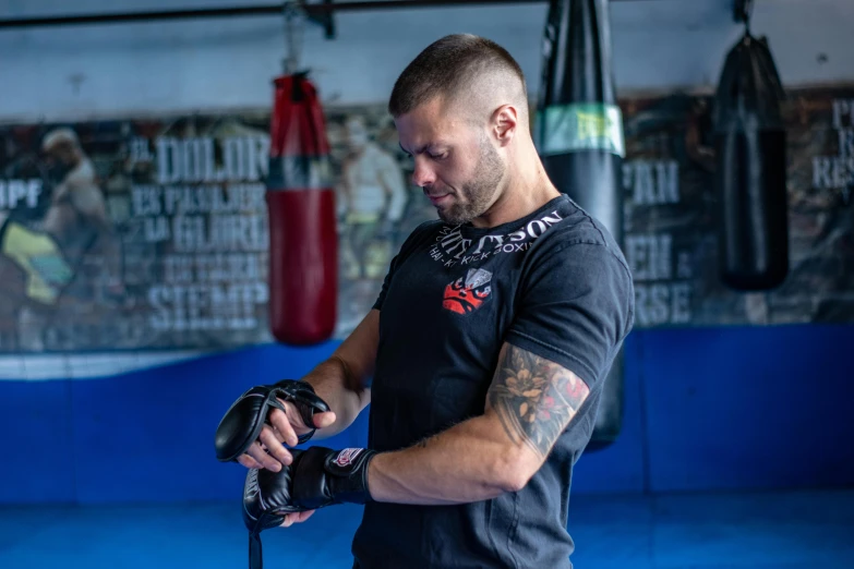 a man with tattoos getting ready to work on a boxing ring