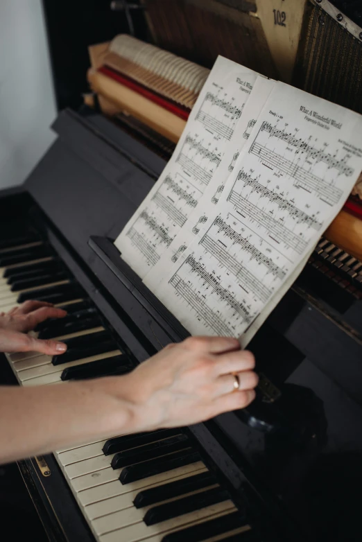 woman holding sheet with piano keys with music score