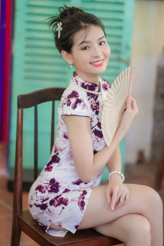 a girl in a white floral dress holds up a fan