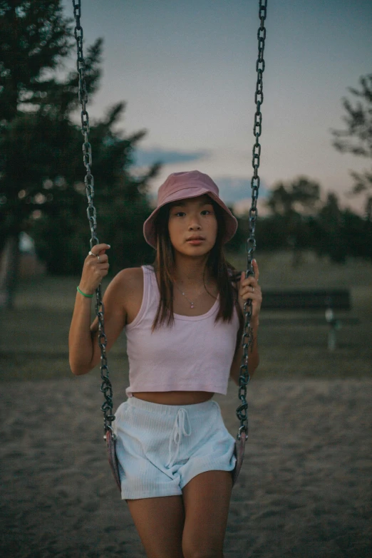 woman wearing a pink hat in swing at sunset