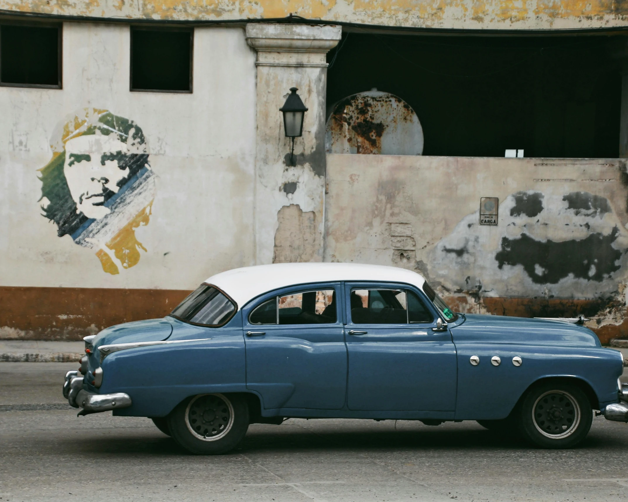 the old car sits parked in front of an old wall