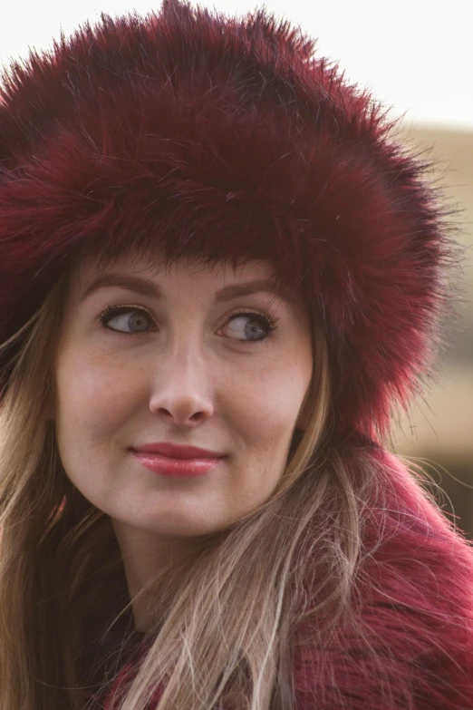 a woman wearing a red fur hat with long hair