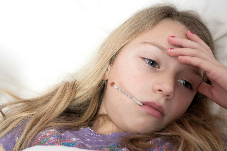 a  is laying down with a thermometer in her ear