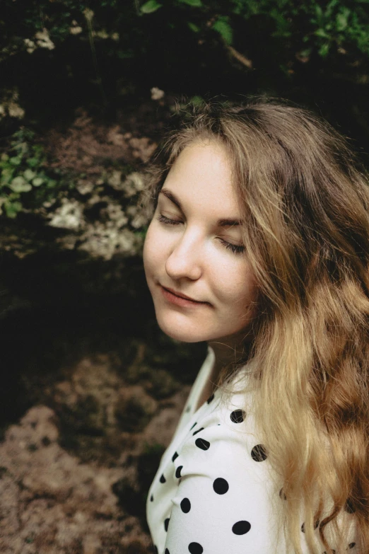 a woman with long hair looks down and smiles