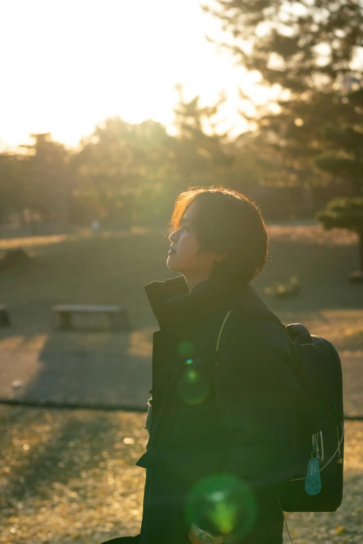 a woman is standing outside with sun in background