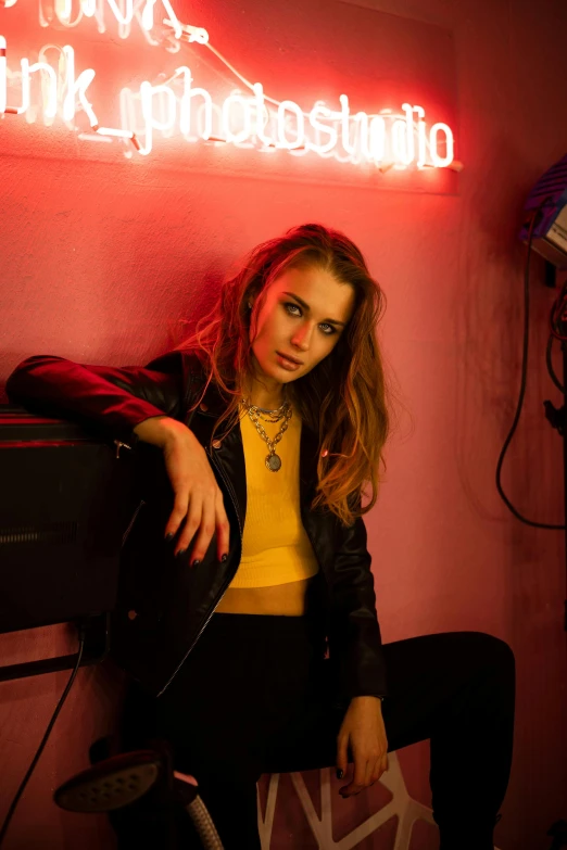 a woman in black leather jacket sitting on counter