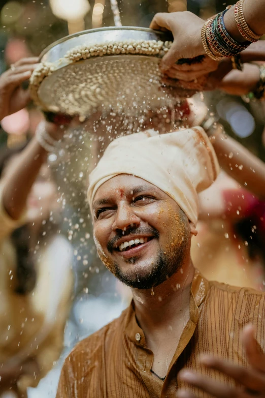 man in indian outfit wearing headgear washing in water