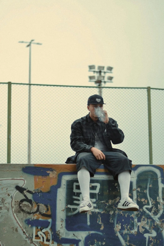 a man sits on a skateboard at the top of a ramp