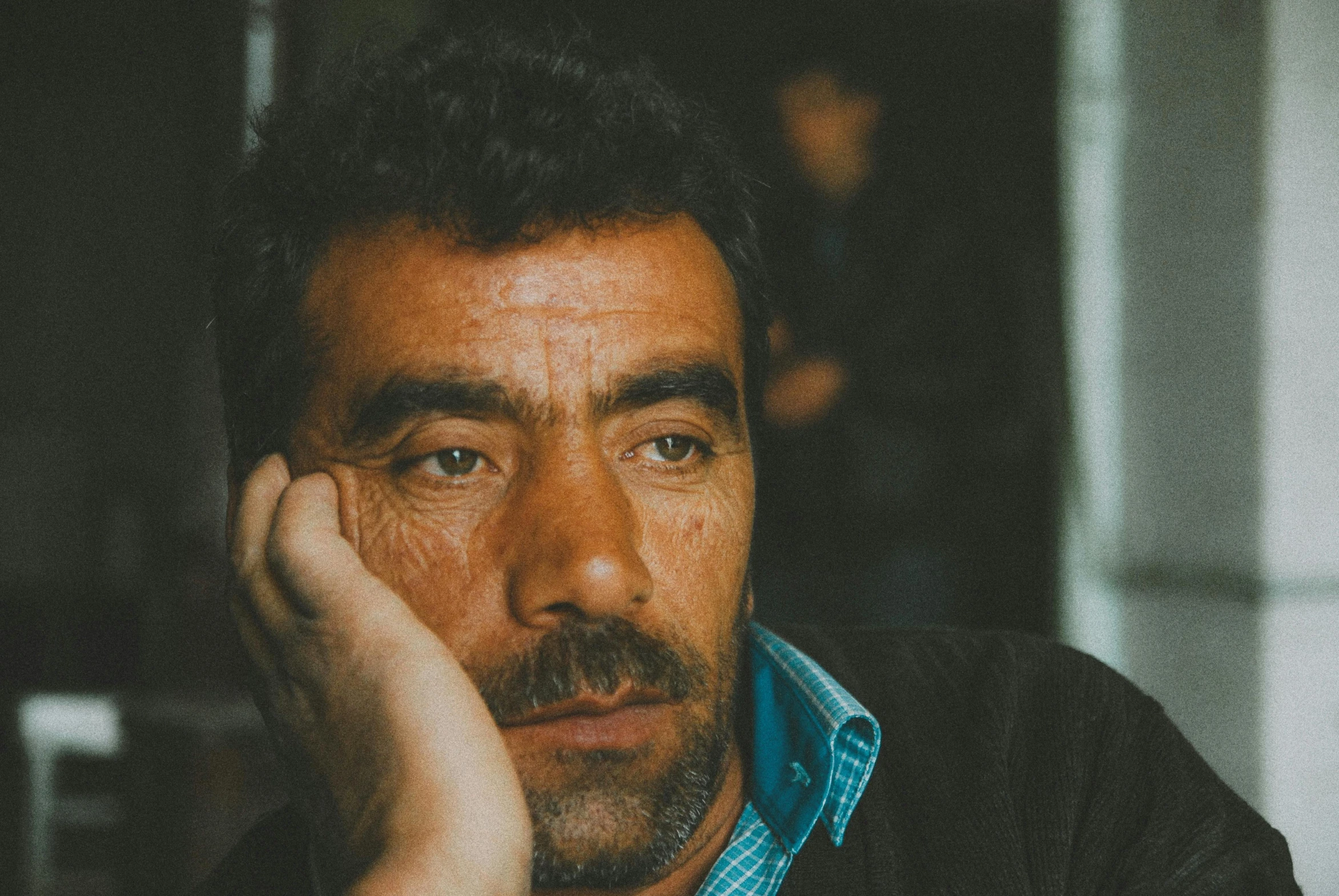 an image of a man sitting with his hand on his face