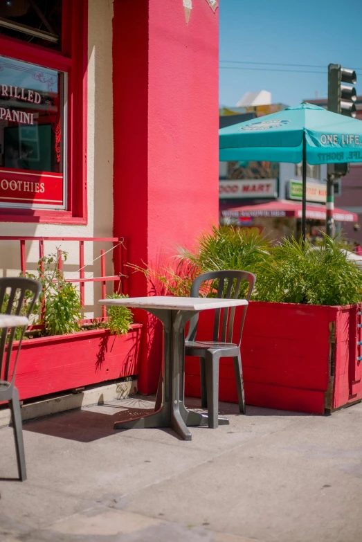 two wooden tables sitting next to each other in front of a red building