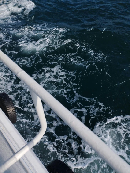 white railing overlooking ocean with water and white boat