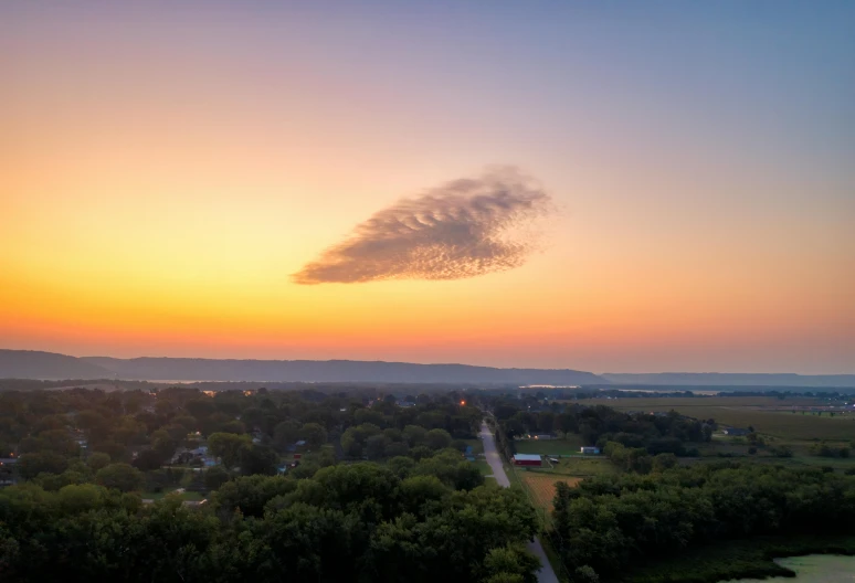 a lone cloud is in the middle of a sunset