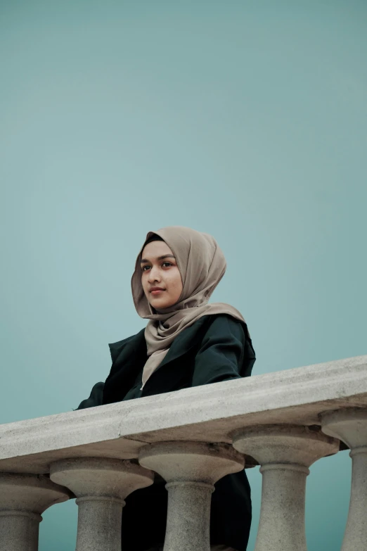 woman with headscarf posing over stone pillars