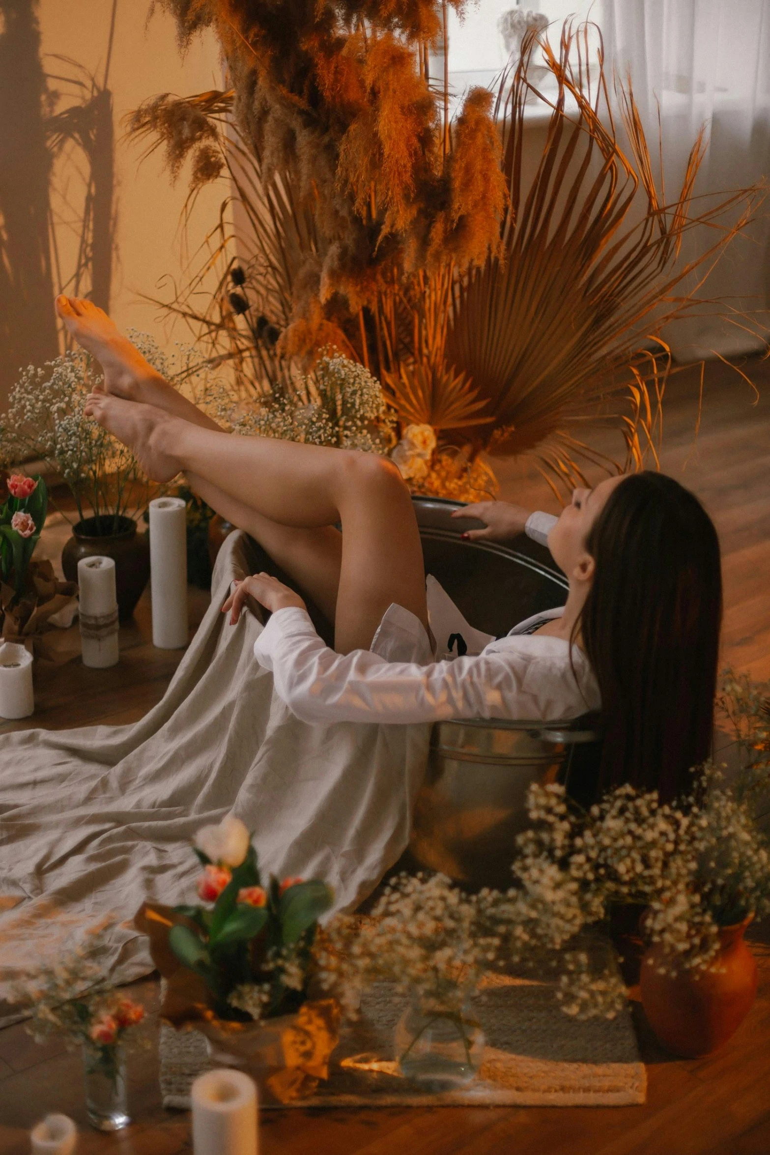 a woman laying in a bath tub next to candles and some flowers