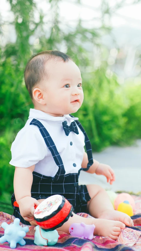 a baby sitting on a blanket next to trees