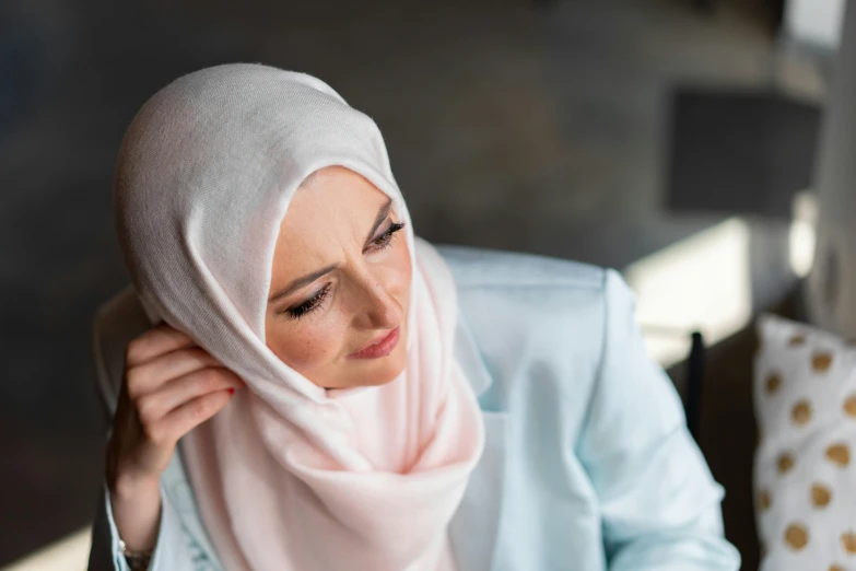 a woman sitting down with a head scarf over her neck