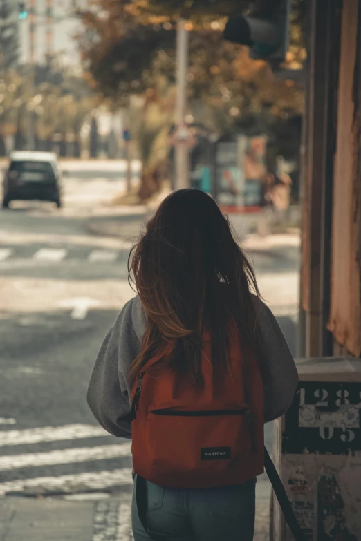 a girl walking down the street with a book bag on her back