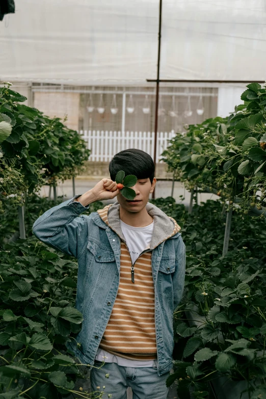 a man holds his head up and stands in the middle of a greenhouse