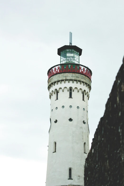 there is a tall white light house with a red top