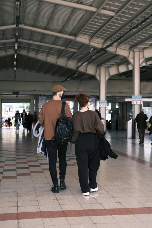 two people walking through an airport talking on cell phones