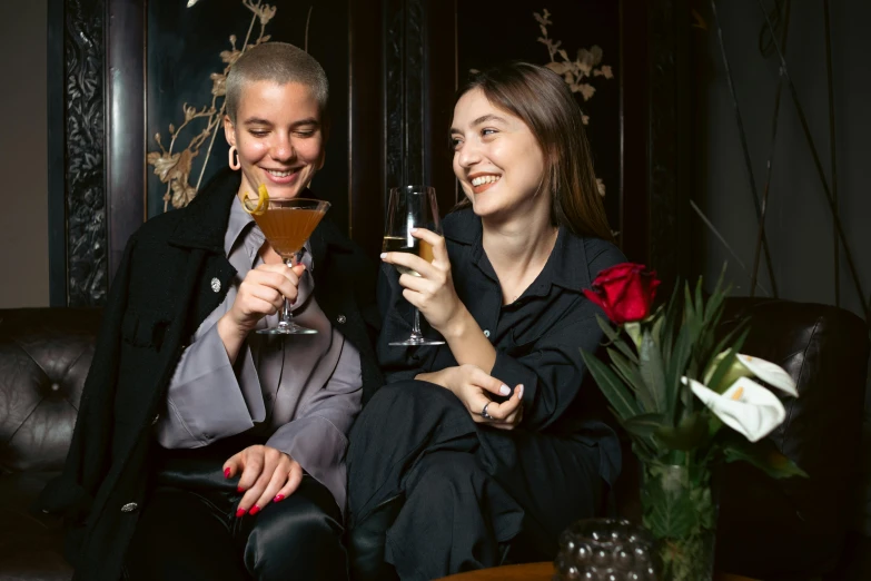 two women sit side by side with drinks