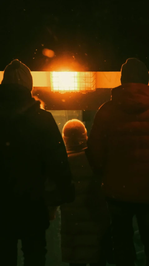 two people standing next to each other on a dark night