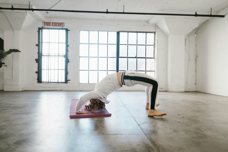 a woman doing a hand stand in the middle of an exercise floor