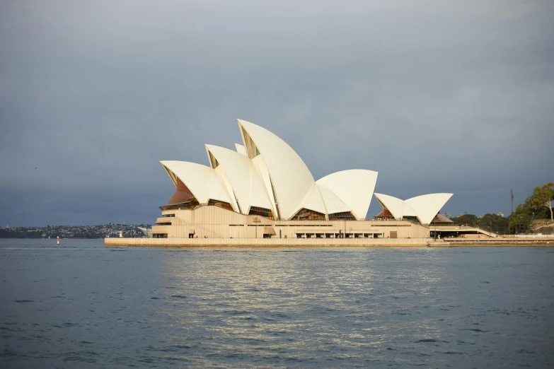 the opera house is on the water with buildings behind it