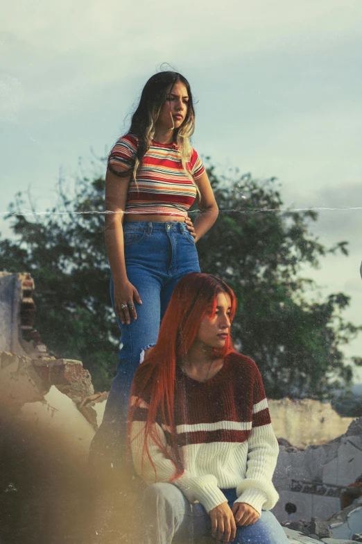 two young women standing and sitting next to each other