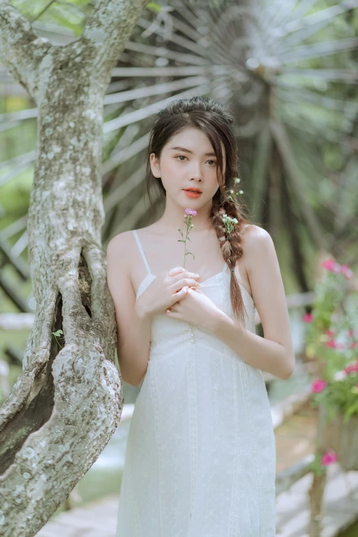 a young asian woman poses under a tree