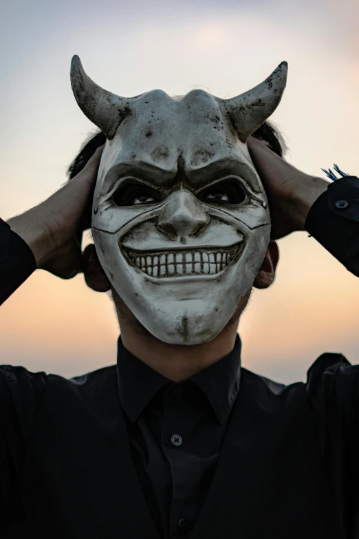 a man wearing white makeup and a demon mask