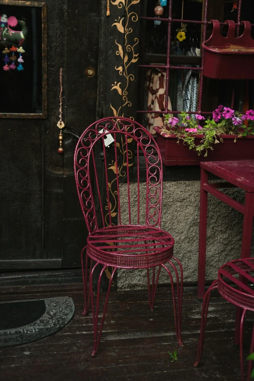 two red wrought iron chairs next to a dark, worn table