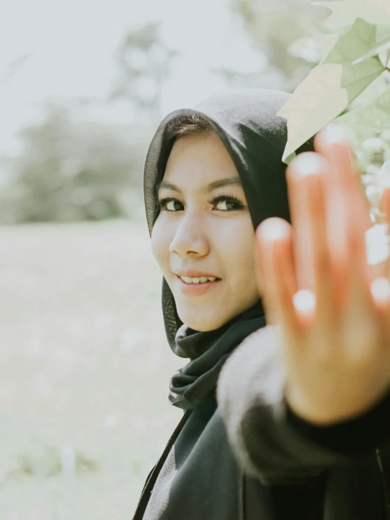 a beautiful woman wearing a black hoodie holding her hands out