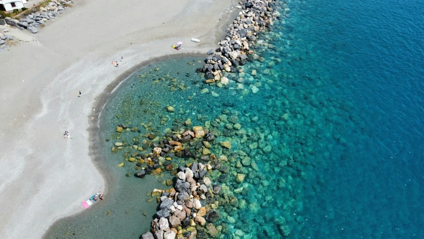 an aerial view of people walking along a shoreline by the water