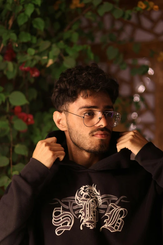 a man wearing glasses while standing under a tree