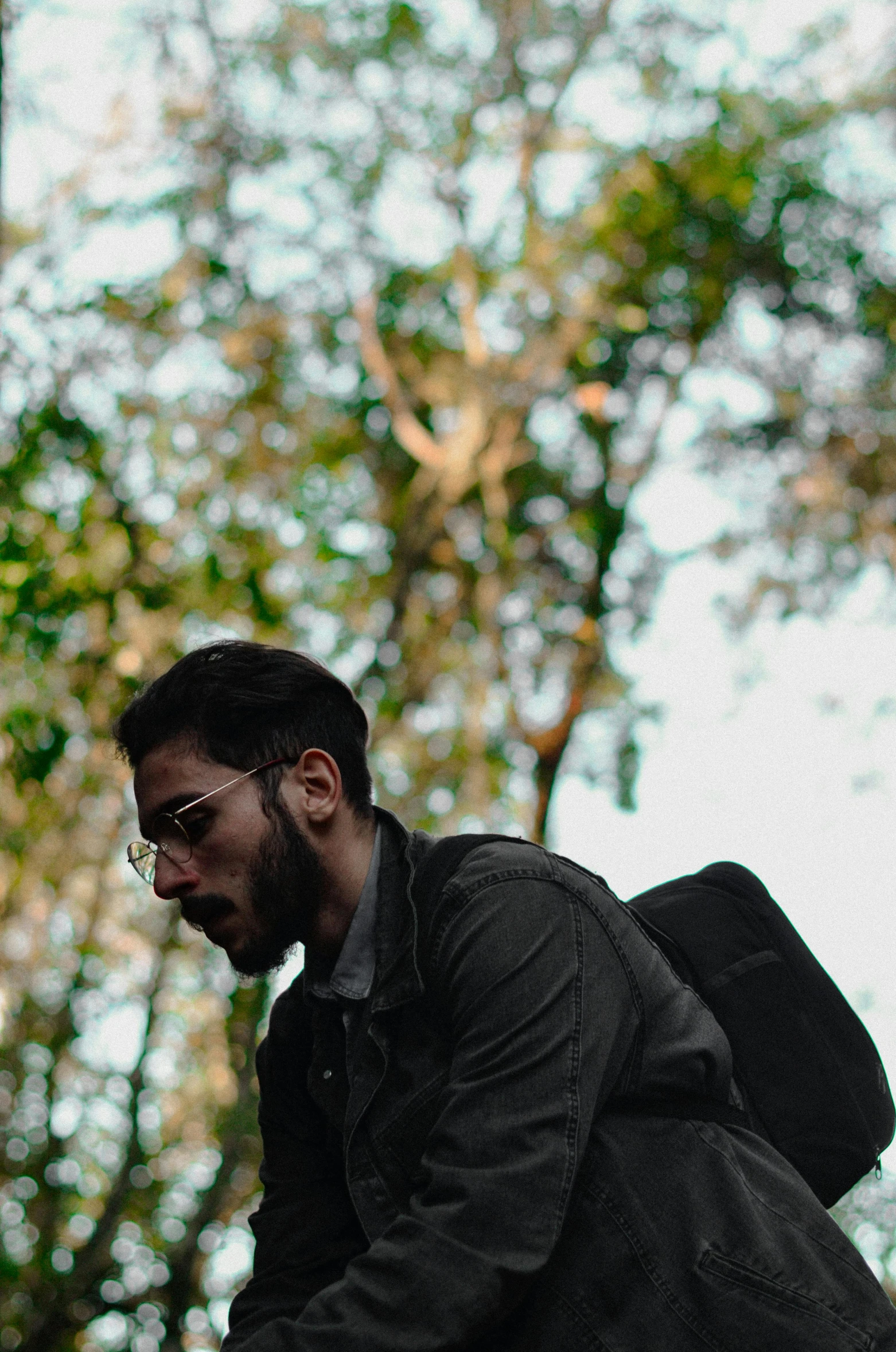 a man with a beard is carrying a bag in the woods