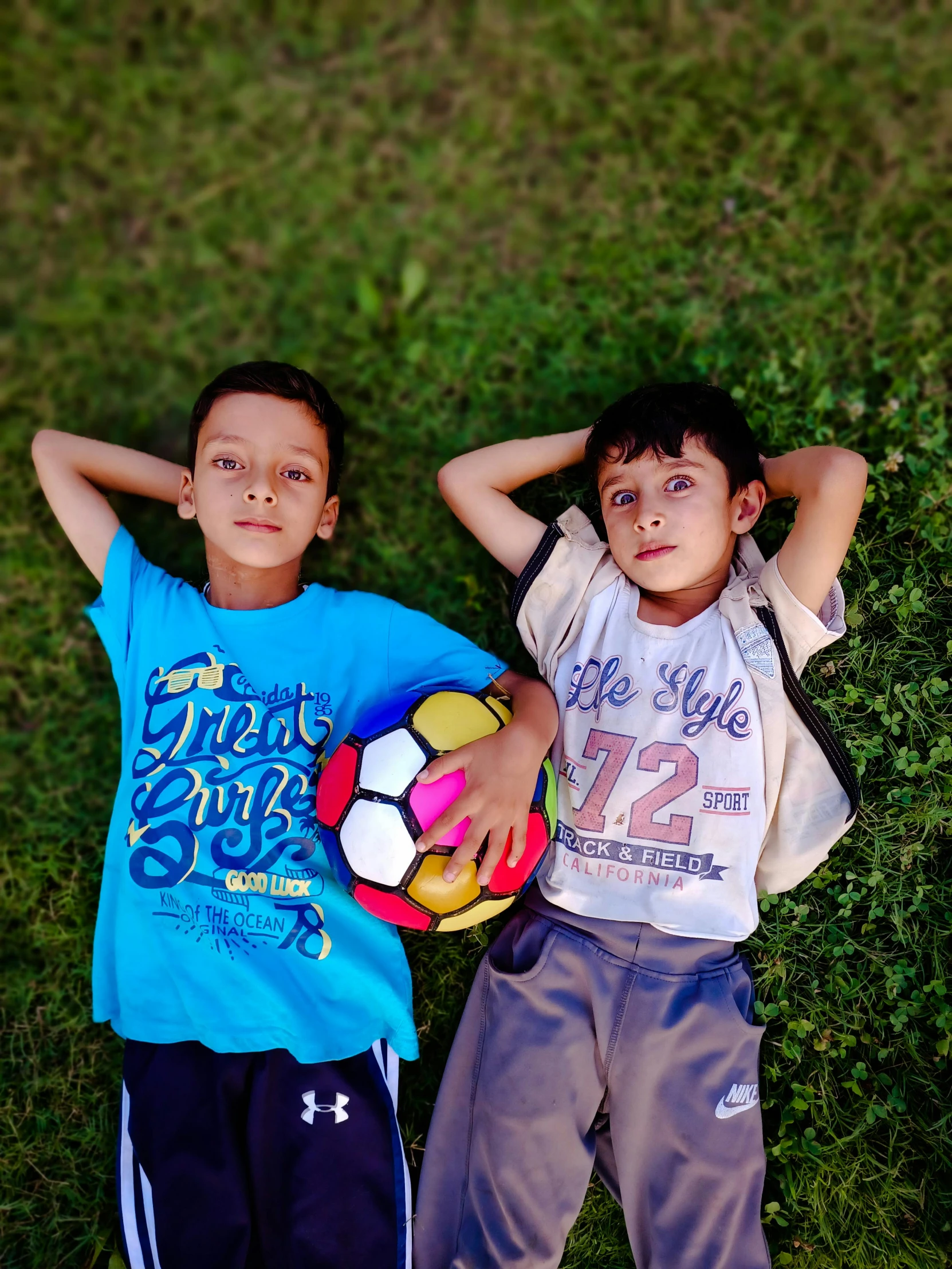 two children are posing for the camera in a grassy area