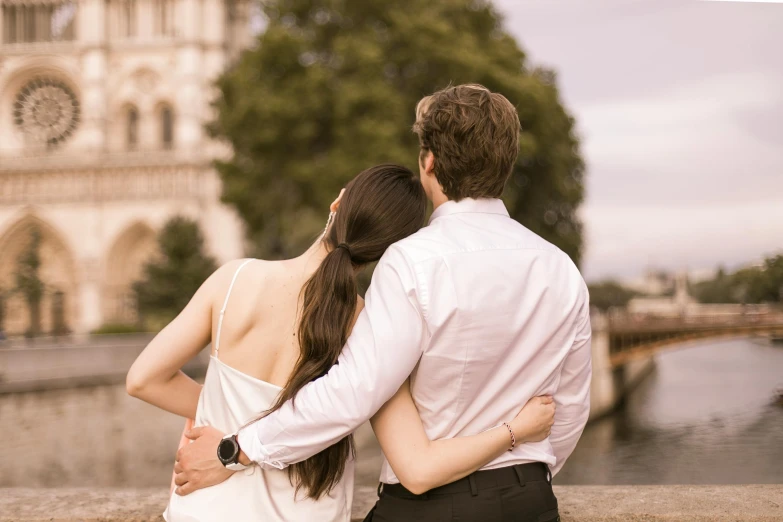 the woman is hugging her man while he watches the bridge