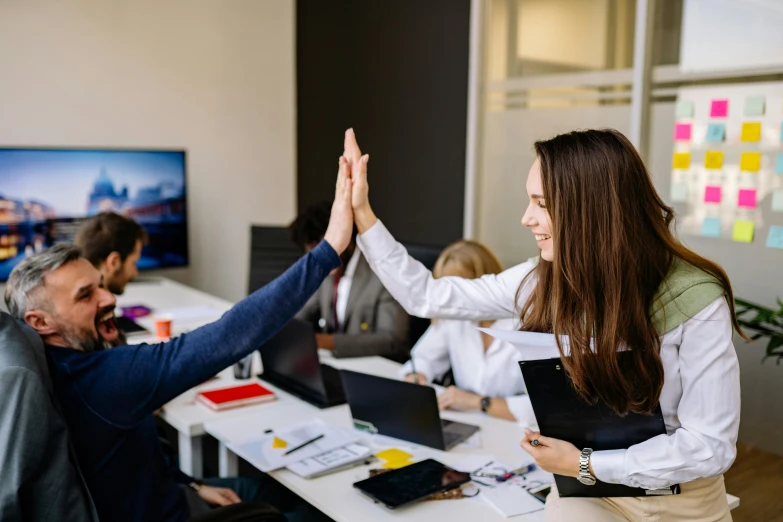 two people on a busy conference room giving each other high five hands