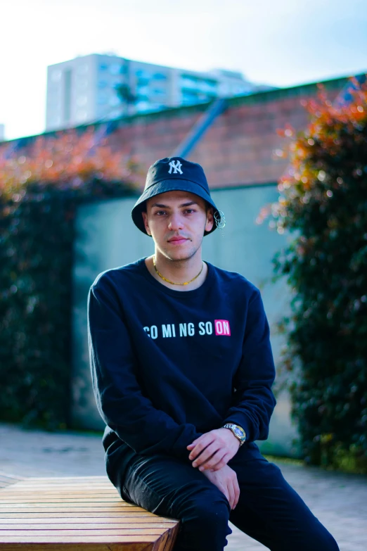 young man sitting on park bench, posing for picture