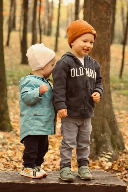 two children who are standing on a wood ledge