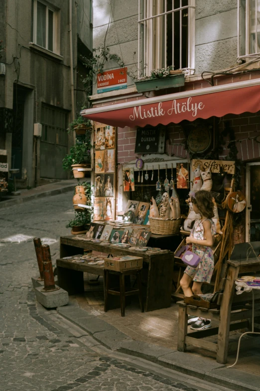 a street vendor sits at a booth on a narrow city street