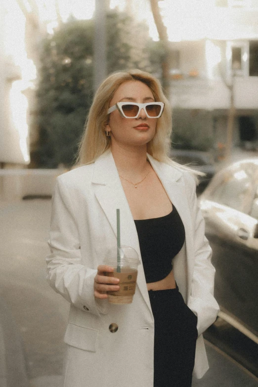 woman in a white blazer holding a drink