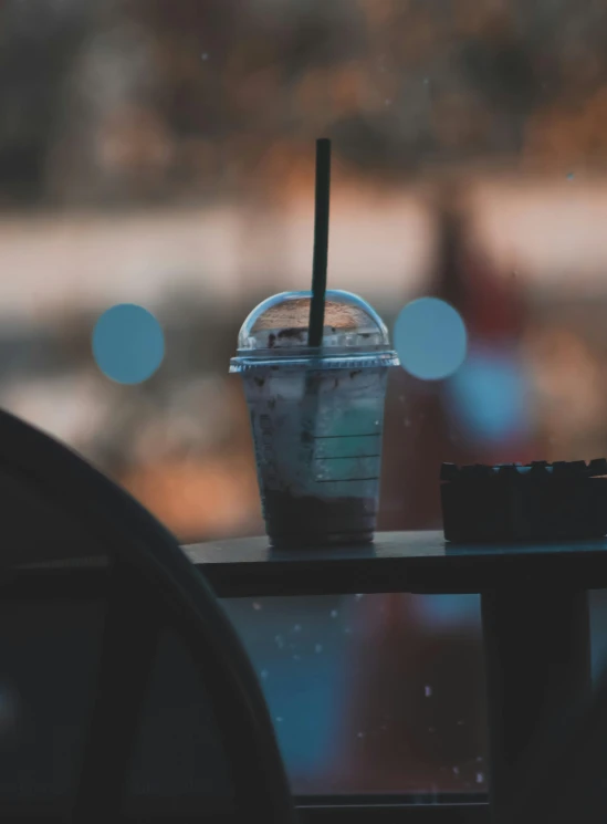 a drink sits on a table near a window