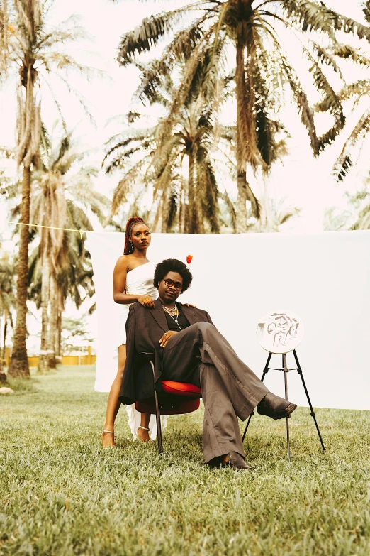 two people sitting in an empty chair in a grassy field