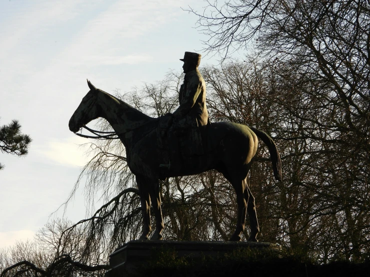 a statue of a man on a horse is next to trees