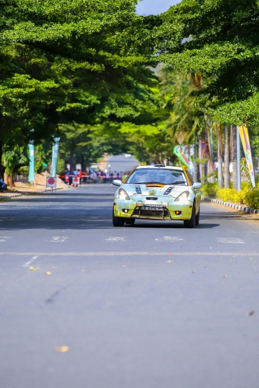 a yellow and white car driving down the street