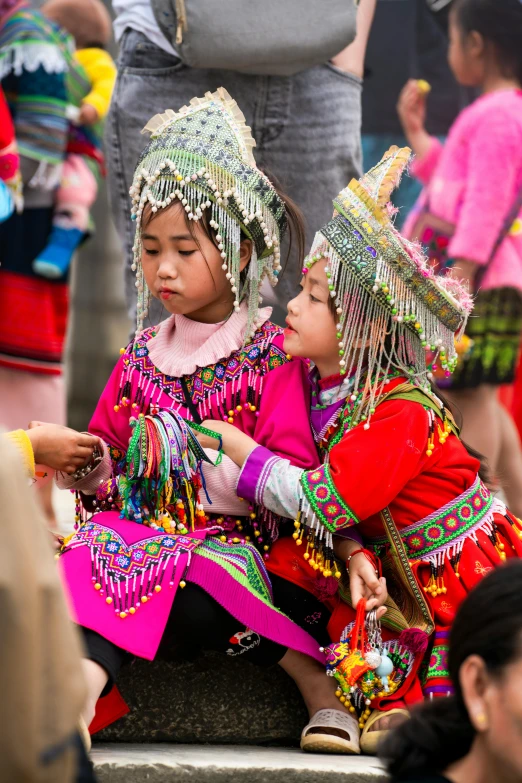 two girls dressed in bright colored clothes are sitting on steps