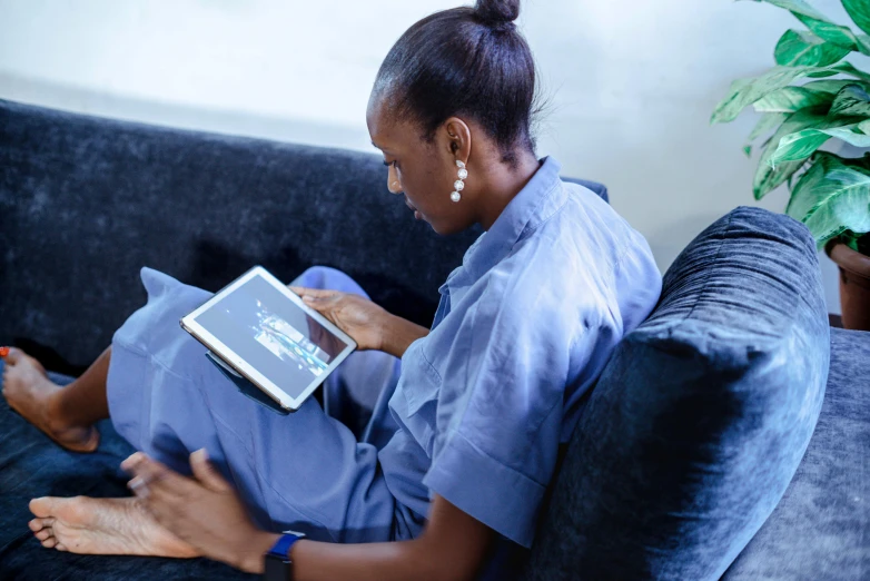 a woman is sitting on a couch using her laptop