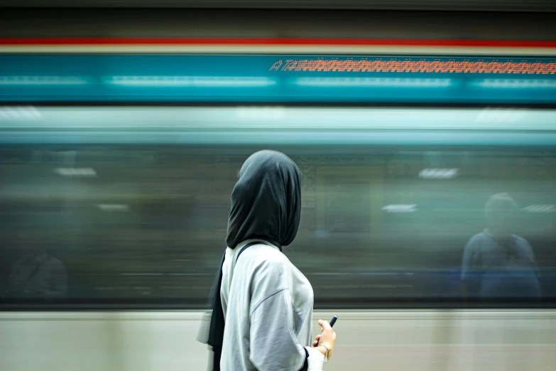 a man standing at a subway station holding a cell phone